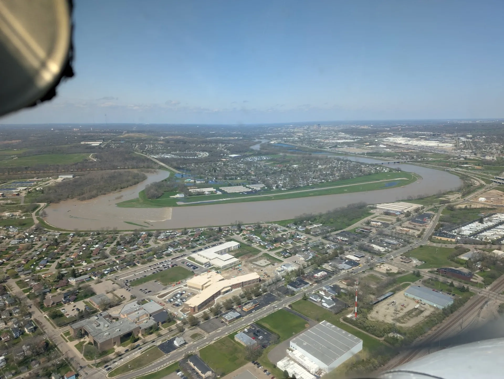 Aerial view of a river bend, an airstrip, and the Dayton skyline on the horizon