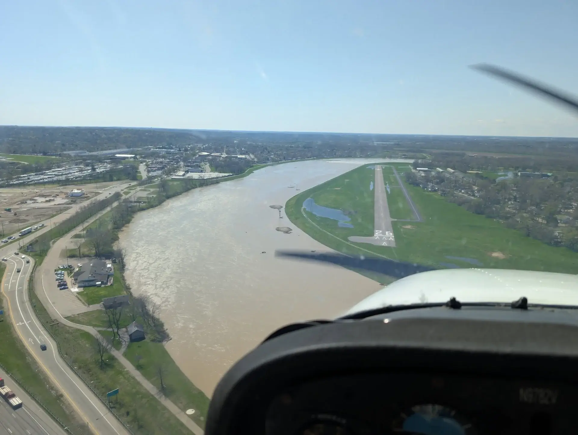 View past the propeller on approach to runway 26 beside the river