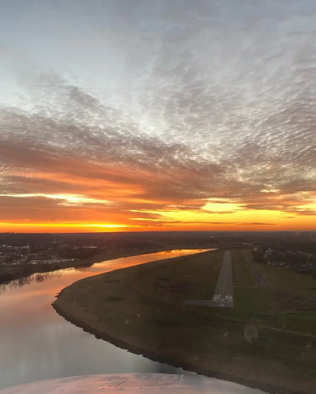 Orange sunset sky over the river and runway 26 on approach
