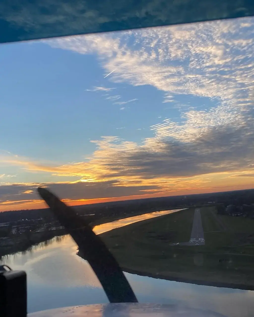 Sunset sky over the river with runway 26 ahead past the propeller